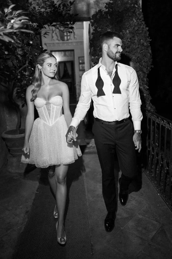 Bride and groom in their evening looks walking hand in hand during the afterparty at Borgo Stomenanno.