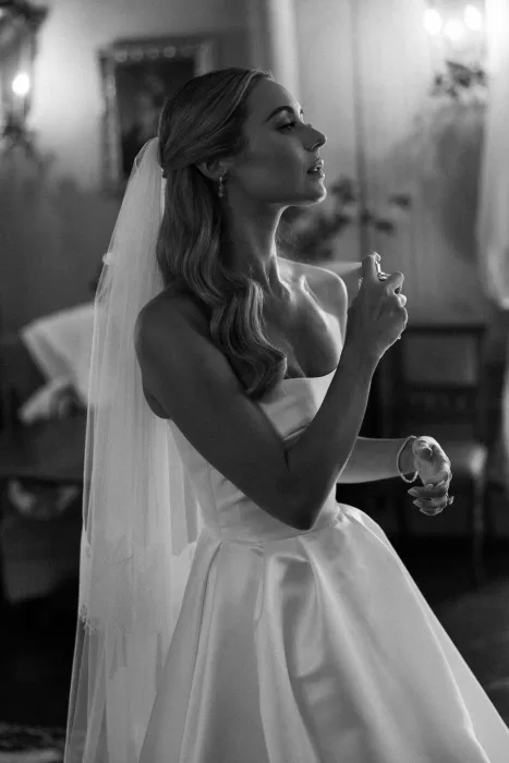 Timeless black-and-white moment of the bride applying perfume before the ceremony at Borgo Stomenanno.
