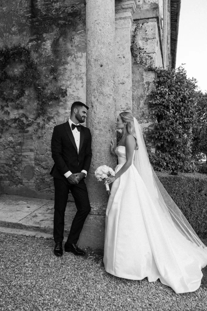The bride and groom share an intimate moment beside the rustic stone walls of Borgo Stomenanno.