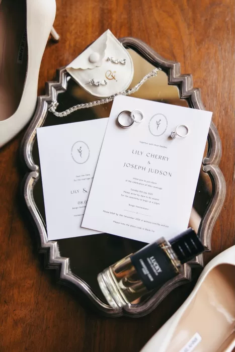 Elegant flatlay with wedding invitations, rings, perfume, and accessories at Borgo Stomenanno.