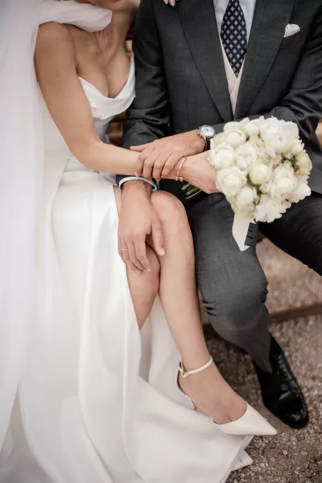 Intimate moment of the bride holding her bouquet while linking arms with the groom, seated at Cigarral de la Mercedes.