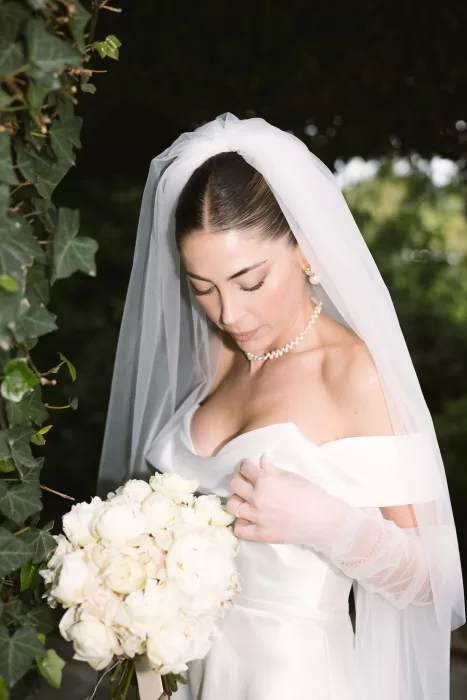 Timeless bridal portrait with white rose bouquet, captured in the gardens of Cigarral de la Mercedes.