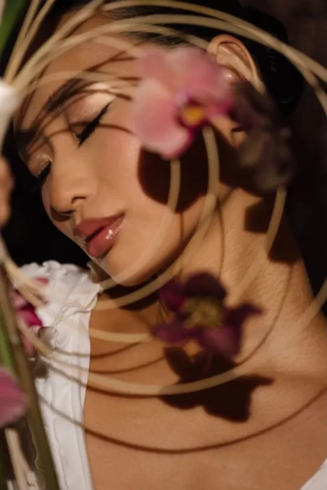 Artistic close-up of bride with eyes closed, framed by curved orchid bouquet, photographed by Sergey Skripnik.