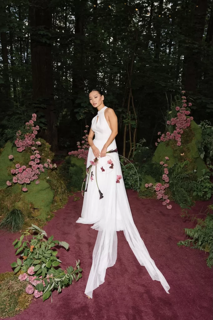 Bride in elegant white gown holding modern bouquet on moss-lined forest aisle at wedding photographed by Sergey Skripnik.