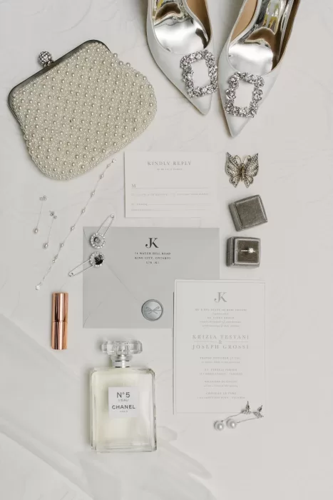 Elegant flat lay of wedding accessories, invitations, and Chanel perfume for a celebration at Château Le Parc.