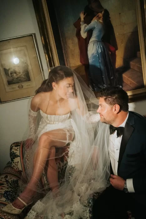 Intimate moment between bride and groom under a painting at Château Ste. Agnès, her veil softly draped around them.