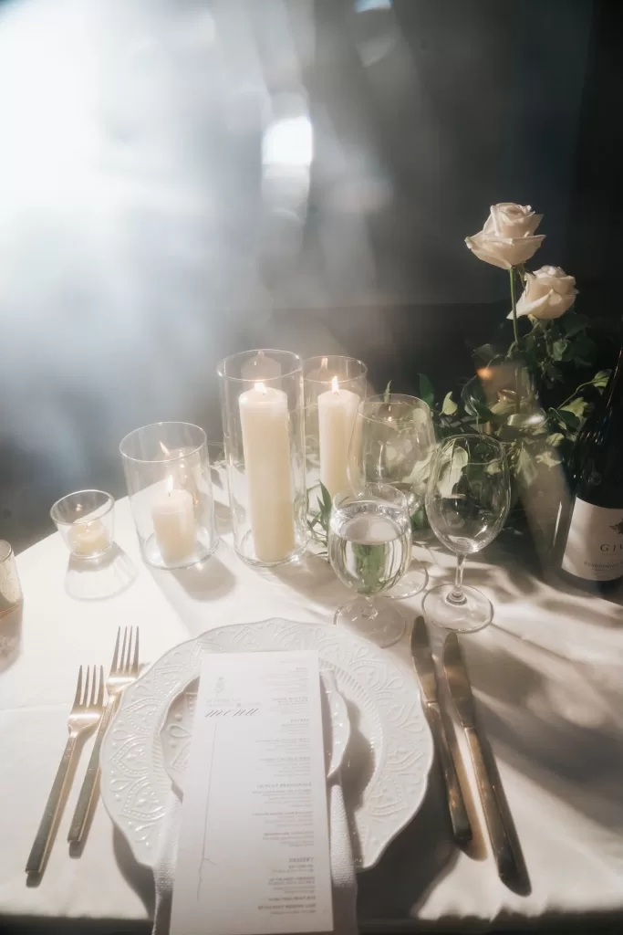 Soft candlelight and white roses on an elegant wedding dinner table at Château Ste. Agnès, creating a dreamy and intimate ambiance.