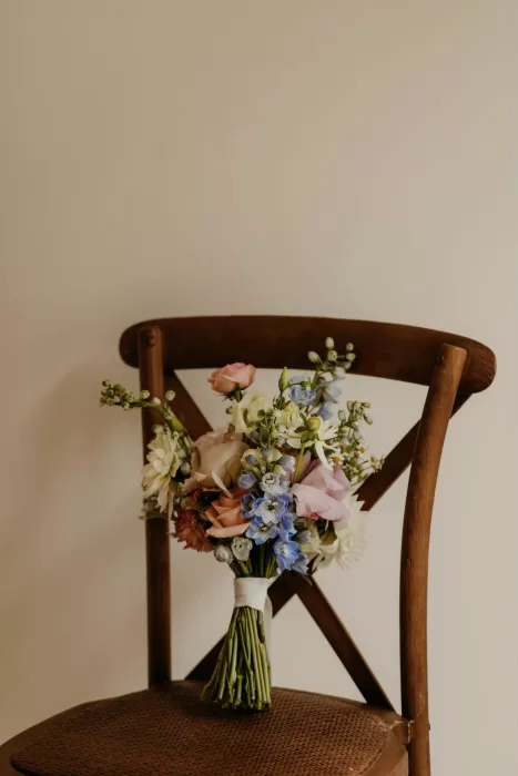 Colorful pastel bridal bouquet resting on wooden chair at Cigarral de las Mercedes.