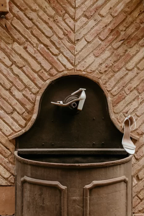 White bridal heels styled against rustic brick wall at Cigarral de las Mercedes.