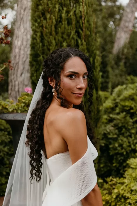Bride with loose curls and elegant veil posing in the gardens of Cigarral de las Mercedes.