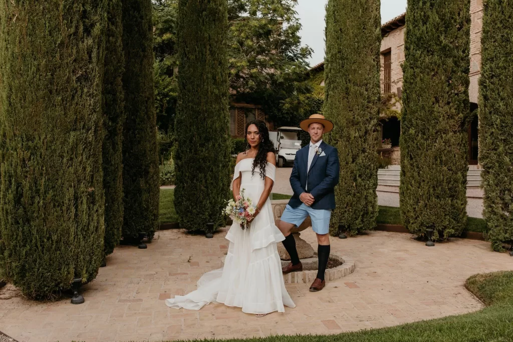 Bride and groom posing among tall cypress trees at Cigarral de las Mercedes.