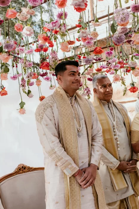 Groom stands beneath a floral mandap of suspended roses during the Hindu ceremony at Cigarral de las Mercedes.