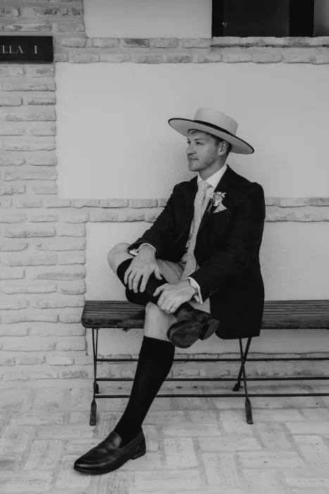 Groom in navy suit with straw hat smiling at Cigarral de las Mercedes.
