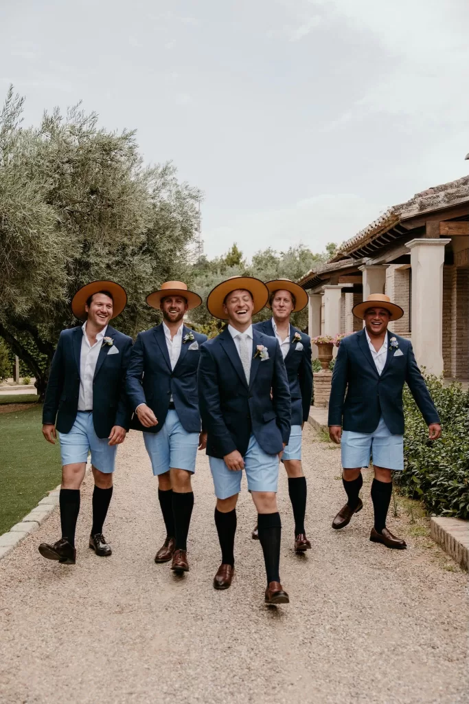 Groomsmen in blue jackets and Spanish hats walking together at Cigarral de las Mercedes.