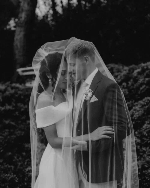 Romantic black and white photo of couple embracing under the bride’s veil at Cigarral de las Mercedes.