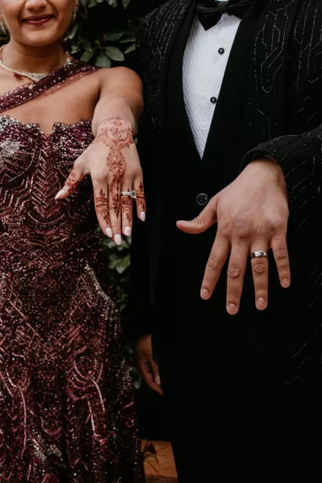 Close-up of the couple showing off their wedding rings and mehndi, dressed in glamorous attire at Cigarral de las Mercedes.