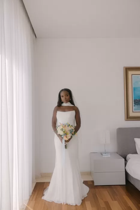 Bride standing indoors in a fitted gown holding pastel bouquet at Coral Residences.