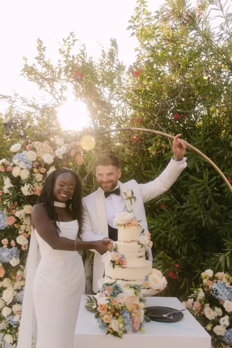 Newlyweds cutting a three-tier floral wedding cake in the garden at Coral Residences.