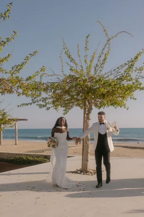 Newlyweds joyfully entering their beachside wedding venue at Coral Residences.