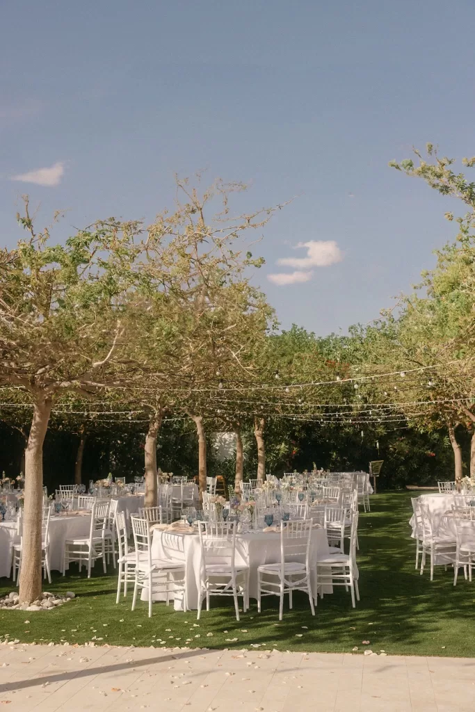 Elegant outdoor reception setup under trees with string lights at Coral Residences.
