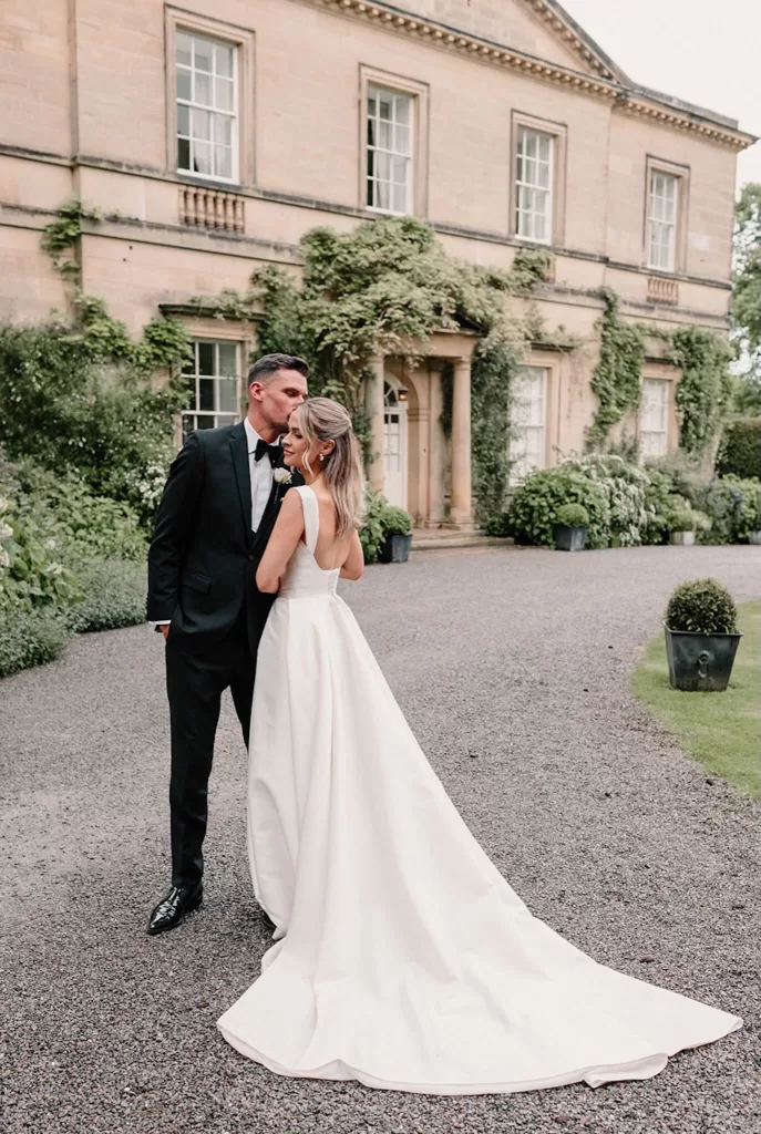 Groom kissing bride’s forehead outside the historic Middleton Lodge mansion.