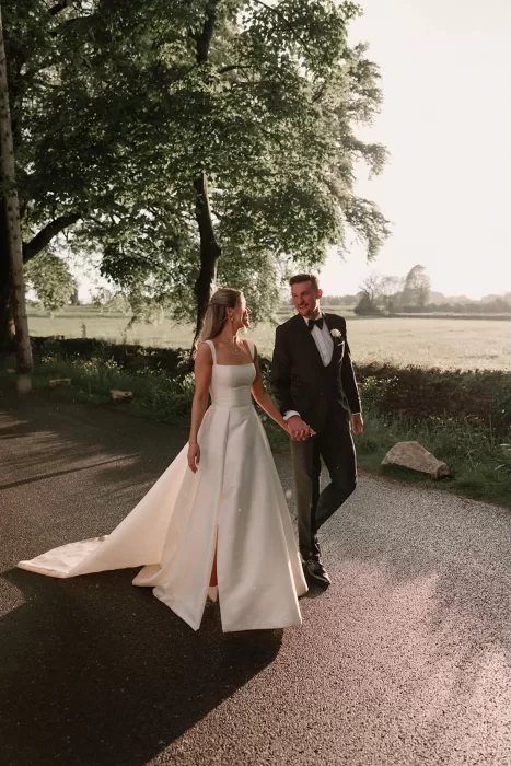 Bride and groom holding hands while walking at sunset at Middleton Lodge.