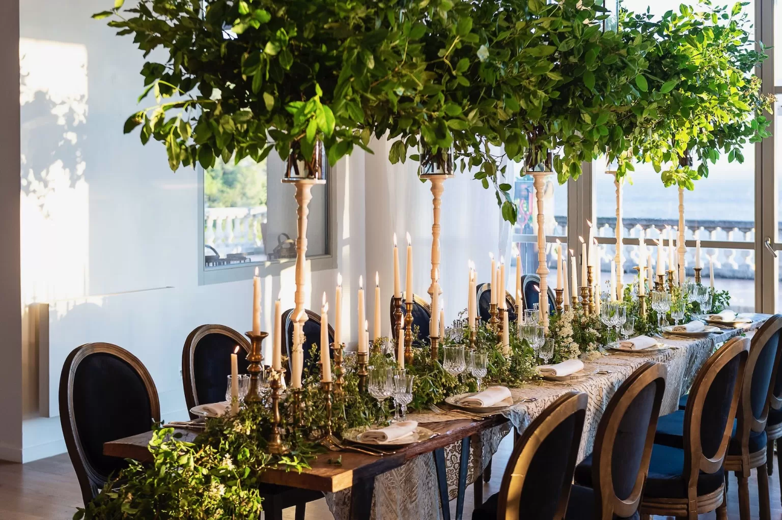Indoor wedding reception at Domaine de Canaille with candlelit tables and tall greenery centrepieces.