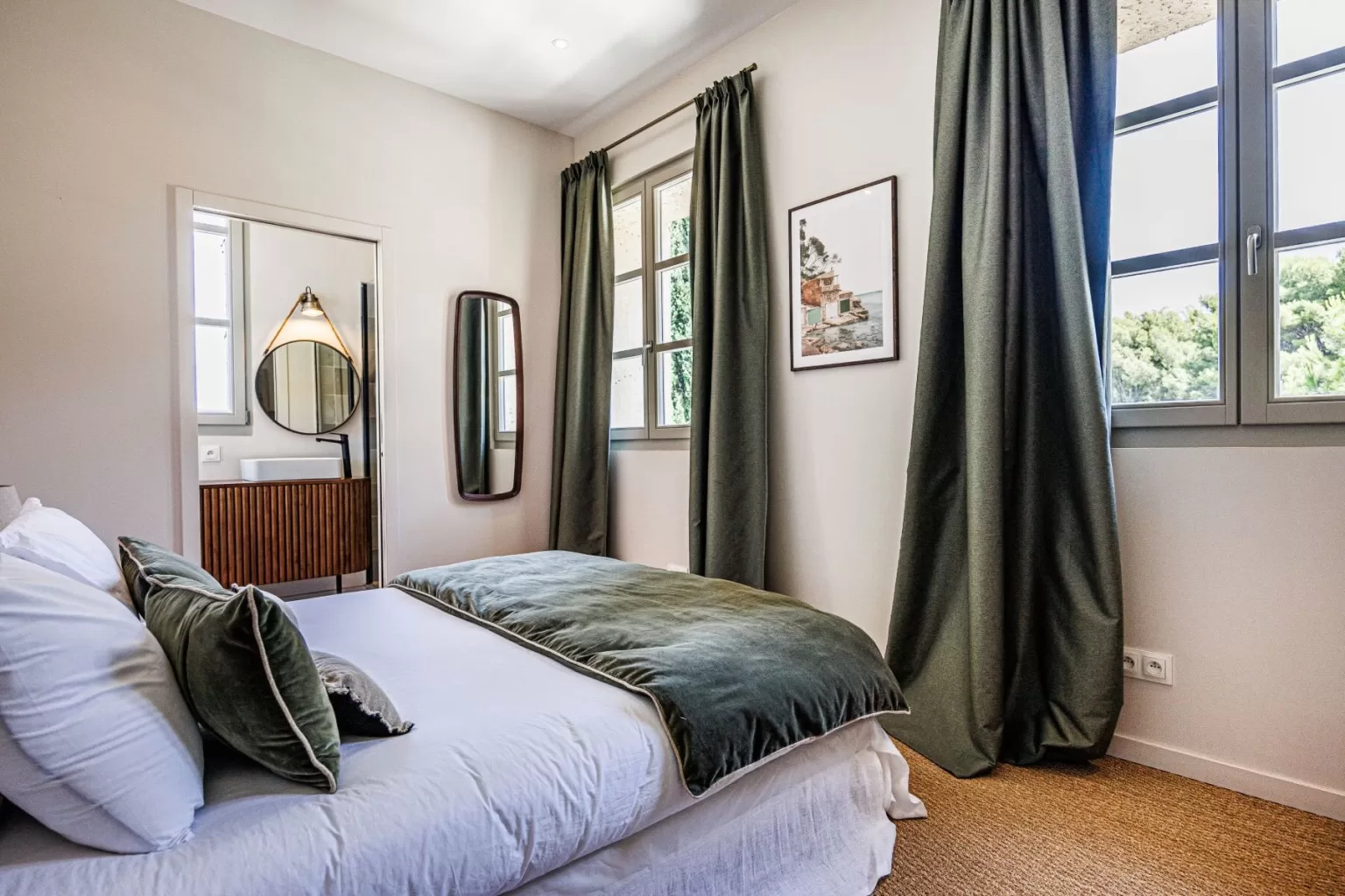 Stylish guest bedroom at Domaine de Canaille with green velvet accents and garden views.