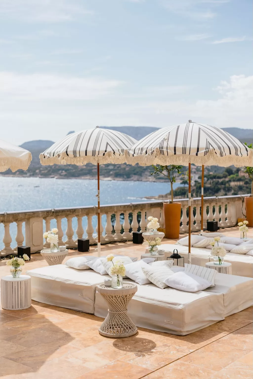 Chic lounge setup on the terrace at Domaine de Canaille with striped parasols and sea views.