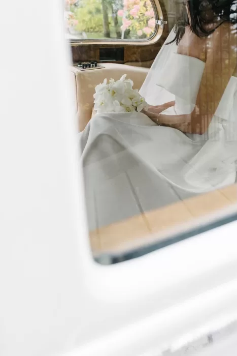 Bride sitting inside a vintage car holding her bouquet before arriving at Graydon Hall.