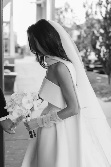 Black and white photo of the bride holding a bouquet of orchids before the ceremony at Graydon Hall.