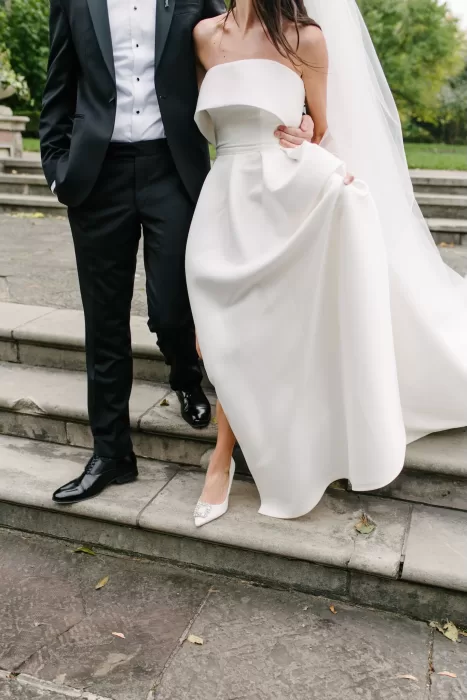 Close-up of the bride and groom descending the stone steps of Graydon Hall, highlighting her gown and embellished heels.