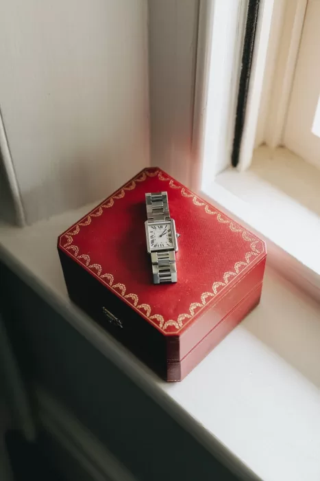 Groom’s elegant silver watch resting on a red Cartier box by a sunlit window at Le Mas Barossa.
