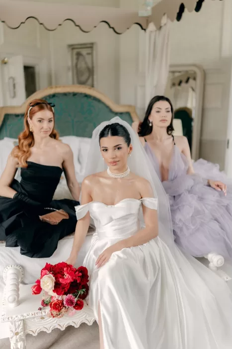 Bride in satin gown with bridesmaids in elegant dresses sitting together at Hedsor House.