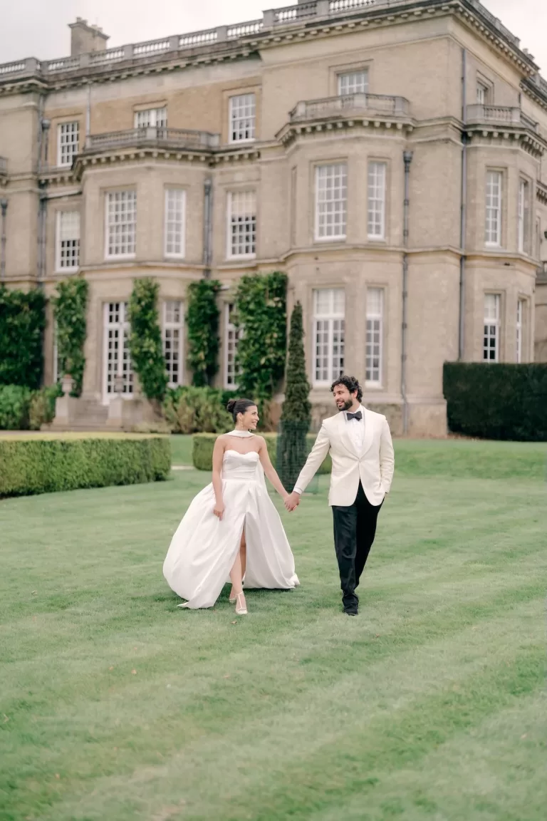 Bride and groom walking hand in hand on the lawn outside Hedsor House.