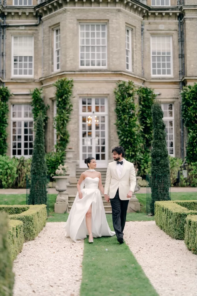 Couple strolling along garden path framed by manicured hedges at Hedsor House.