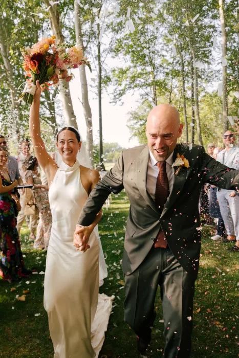 Bride and groom walking hand in hand through confetti after their ceremony at La Farinera de Sant Lluis.