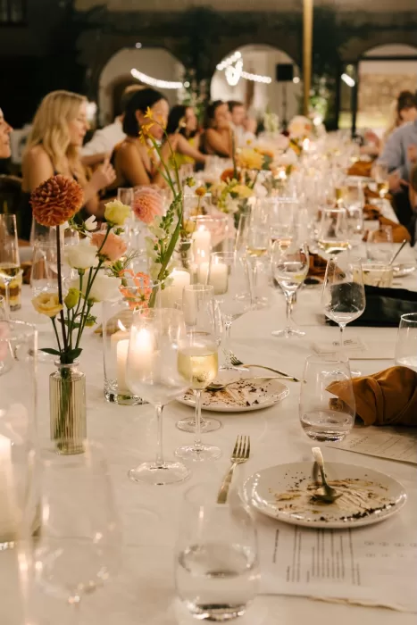 Close-up of a long dinner table with candles, flowers, and wine glasses during the wedding reception at La Farinera de Sant Lluis.