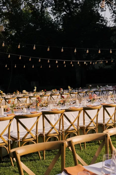 Reception tables with terracotta napkins, flowers, and string lights at La Farinera de Sant Lluis.