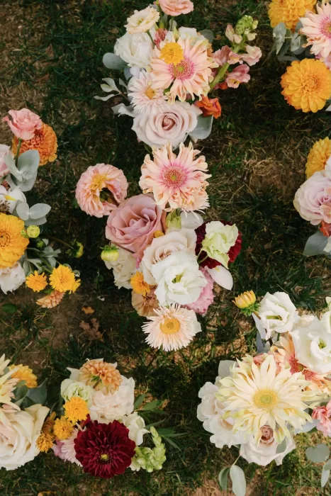 Colorful wedding flowers with dahlias, roses, and zinnias arranged on the lawn at La Farinera de Sant Lluis.