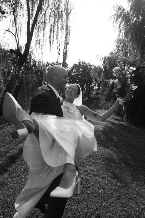 Groom carrying his joyful bride in an outdoor moment at La Farinera de Sant Lluis.