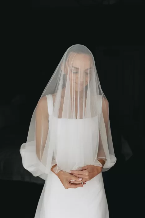 Bride standing gracefully with a sheer veil over her face, softly lit against a dark background at Le Mas Barossa.
