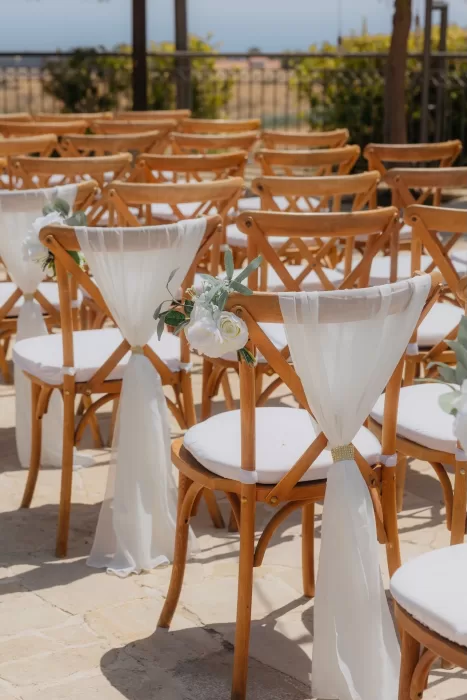 Wedding chairs decorated with white fabric and flowers arranged for a ceremony at Liopetro.
