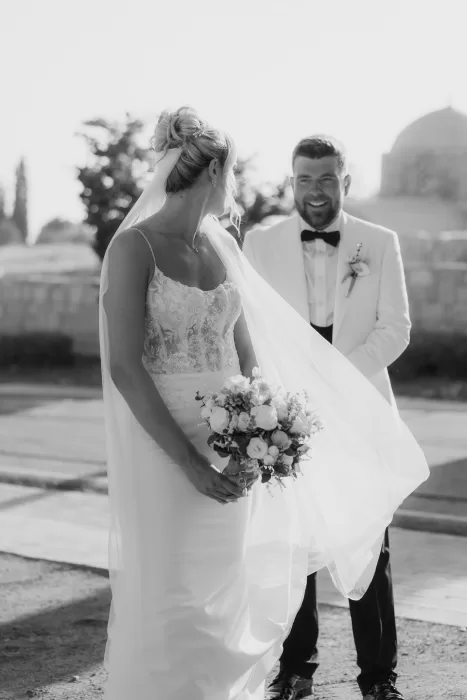 Romantic black and white photo of bride and groom smiling at each other outside Liopetro.