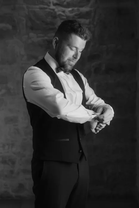 Groom adjusting his cufflinks in a black and white portrait at Liopetro.