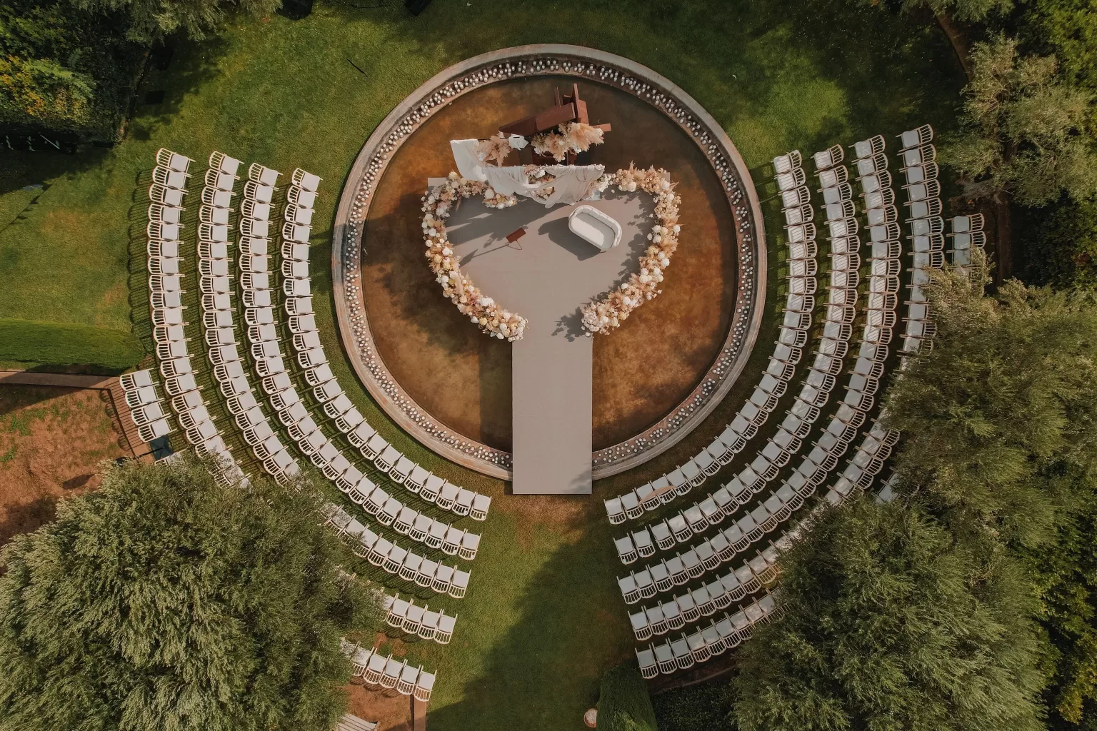Circular ceremony setup with floral arch and white chairs at Mas de Les Voltes.
