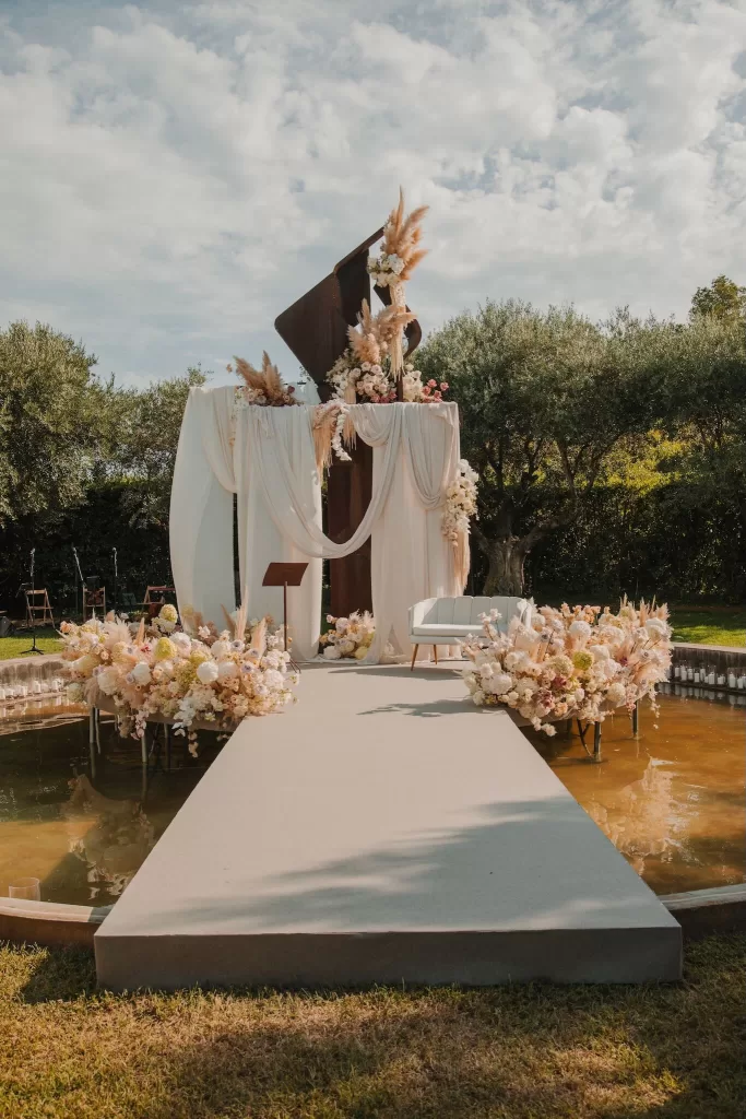 Wedding ceremony stage decorated with draped fabric and flowers at Mas de Les Voltes.