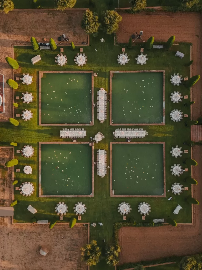 Overhead view of poolside wedding dinner setup with round tables at Mas de Les Voltes.
