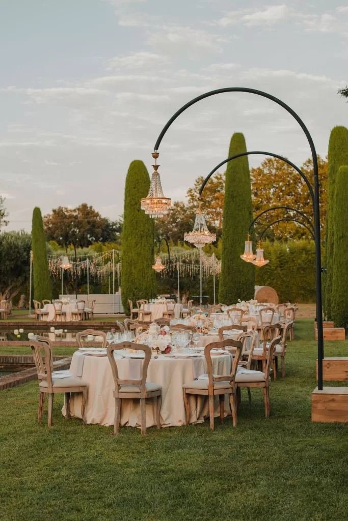 Round wedding tables with chandeliers and soft lighting at Mas de Les Voltes.