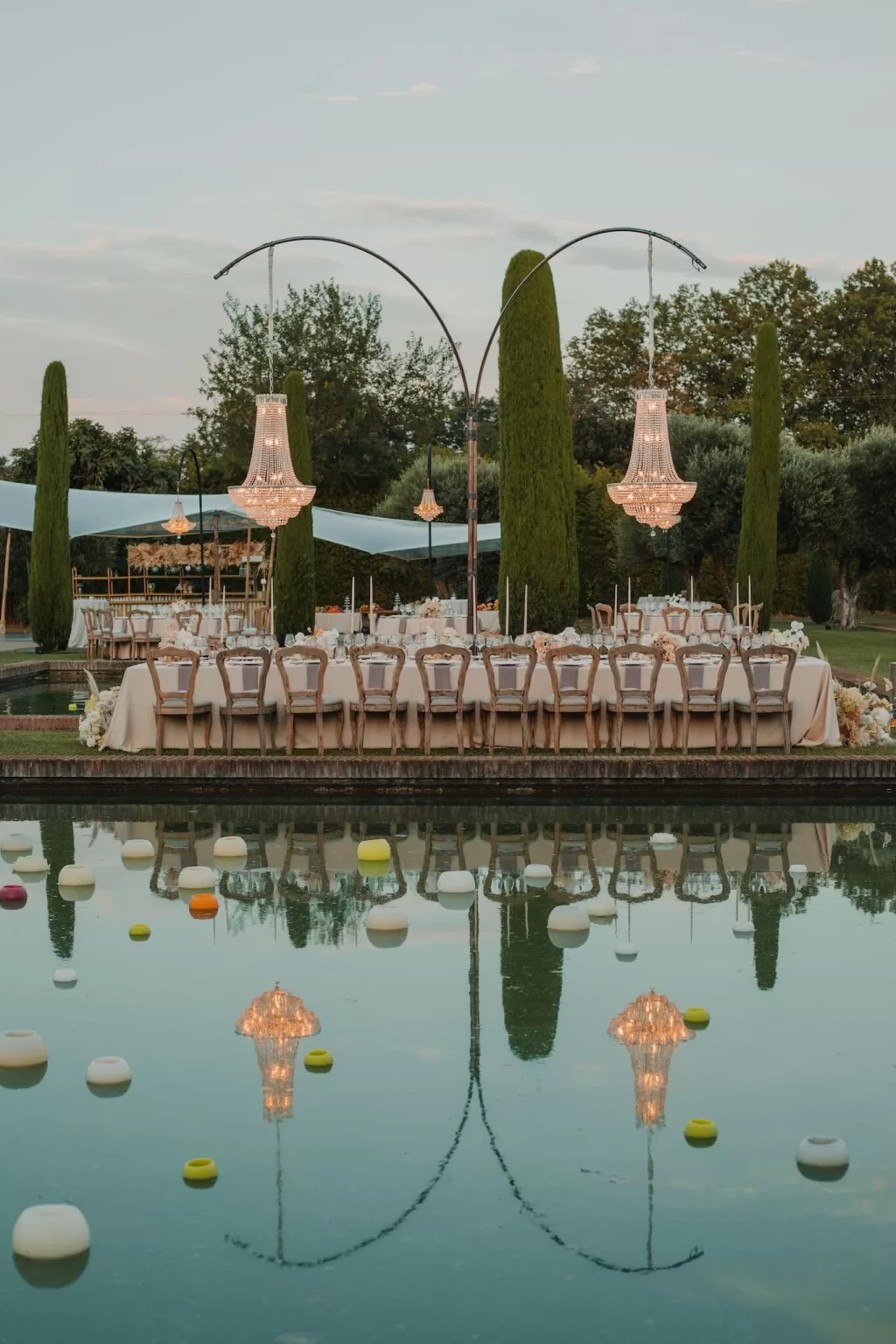 Long wedding table reflected in pools with chandeliers at Mas de Les Voltes.